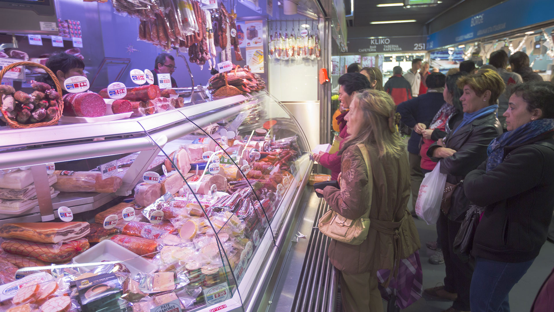 Personas comprando en uno de los puestos de los mercados municipales de Bilbao