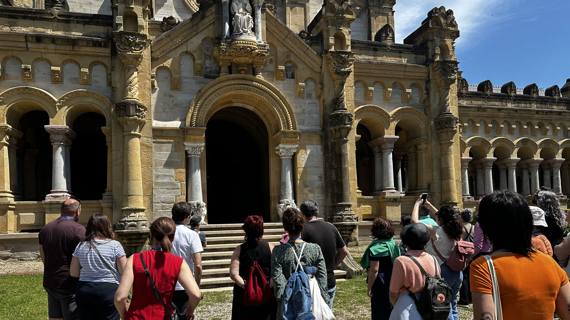 Personas asistentes a una visita guiada al Cementerio de Bilbao contemplando la simbología del edificio principal